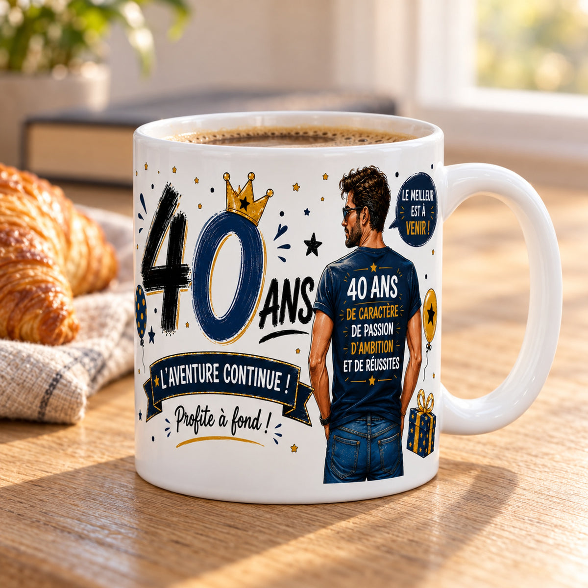 Mug 40 ans Homme « L'Aventure Continue » posé sur une table en bois avec un croissant, pause café