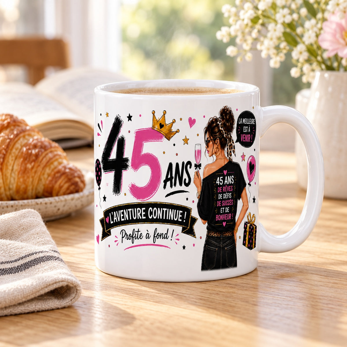 Mug 45 ans Femme « La Meilleure est à Venir » posé sur une table en bois avec un croissant, pause café