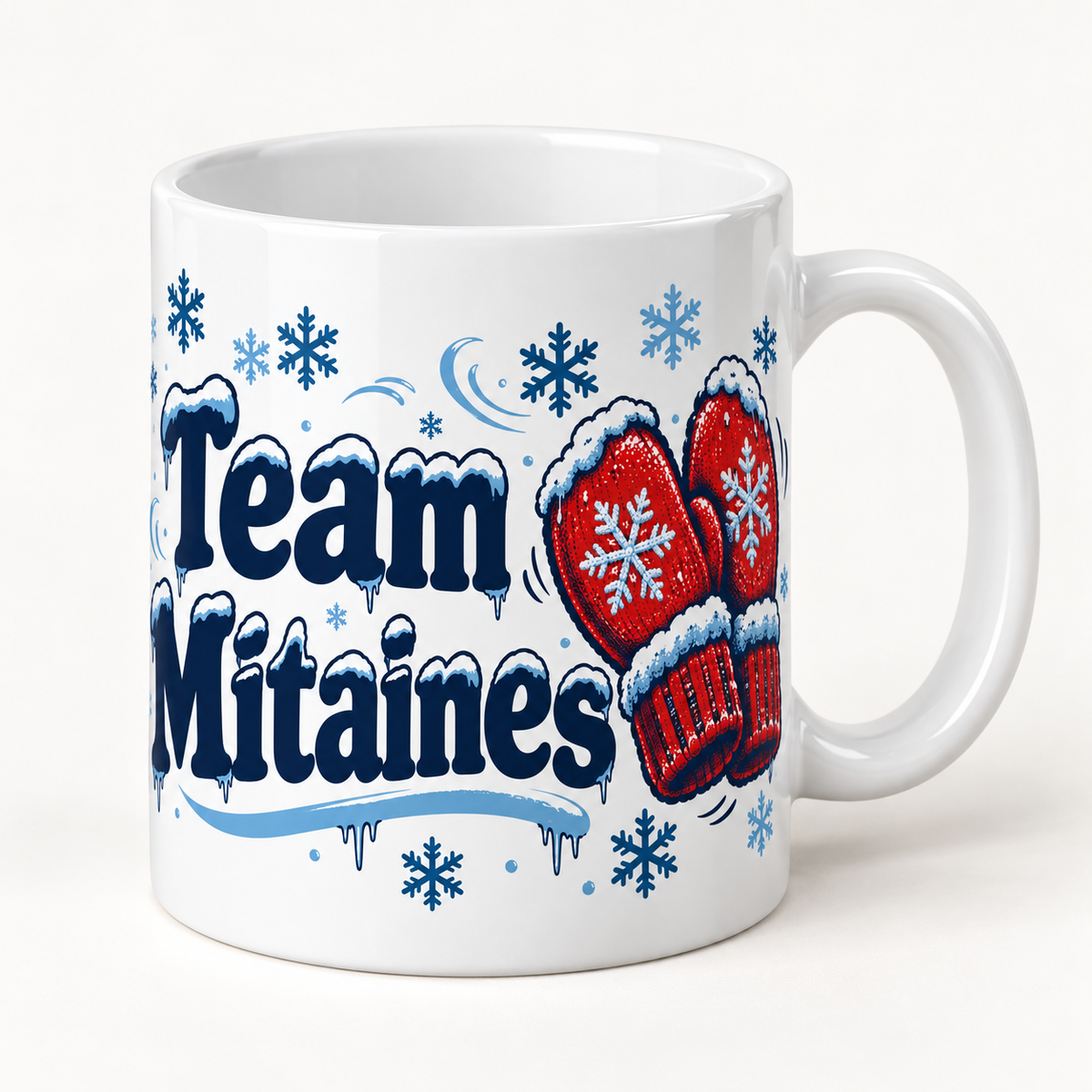 Mug blanc céramique Hiver québécois « Team Mitaines » : une paire de mitaines rouges tricotées, ornées d'un flocon blanc et bordées de neige, côtoie un lettrage « Team Mitaines » bleu nuit givré, au milieu des flocons bleu glacier.