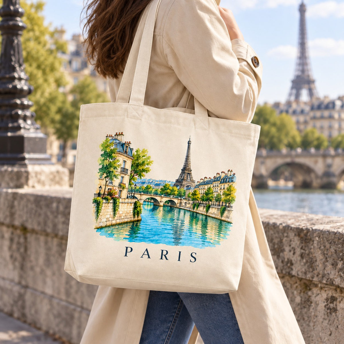 Tote bag Paris Premium porté à l'épaule sur un quai de Seine, tour Eiffel en arrière-plan