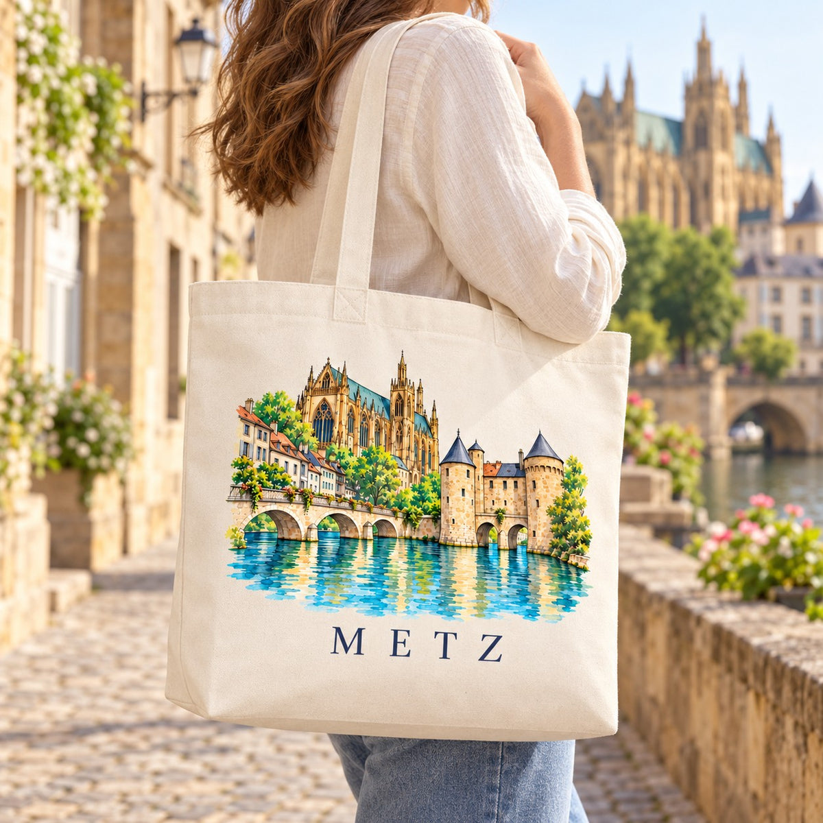 Tote bag Metz Premium porté à l'épaule dans une rue pavée, cathédrale en arrière-plan