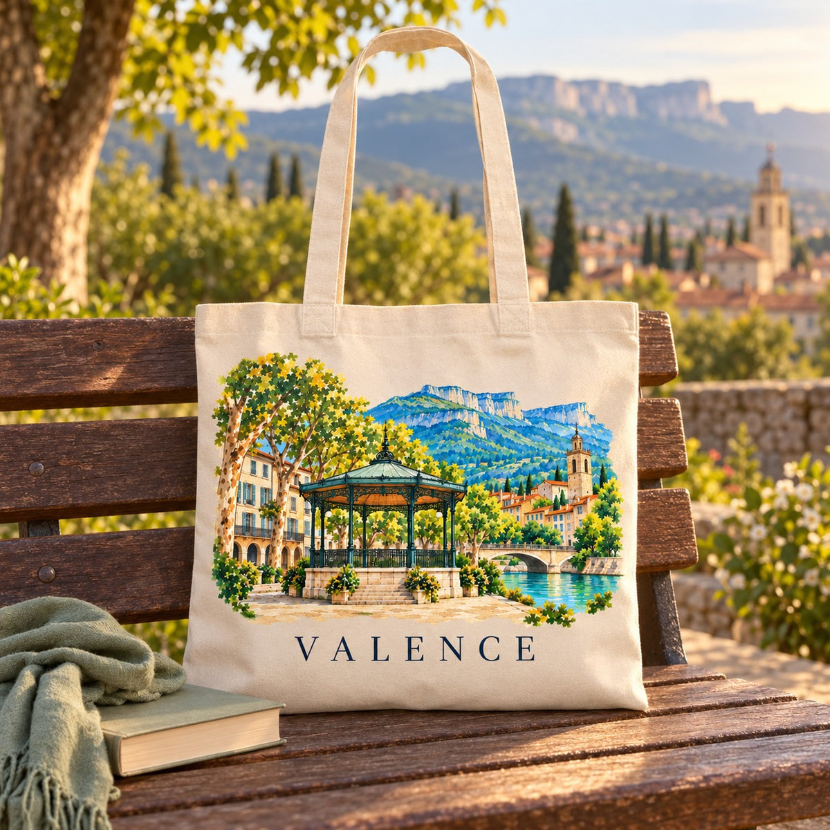 Tote bag Valence Essentiel posé sur un banc face au Vercors, avec un livre et un plaid