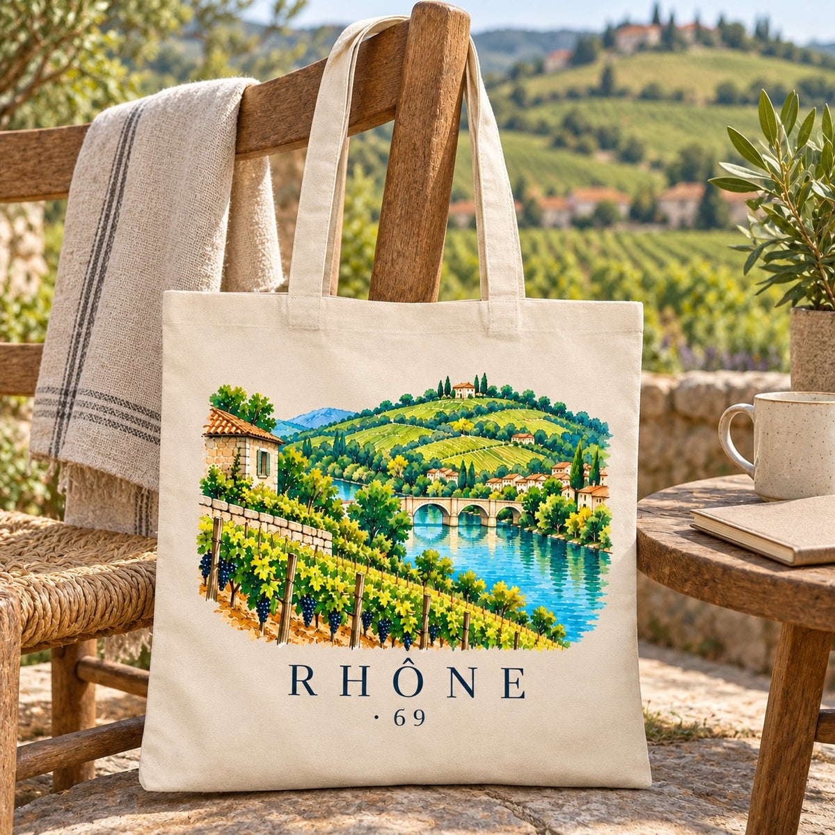 Tote bag Rhône (69) Essentiel suspendu à une chaise paillée face aux coteaux, avec un plaid