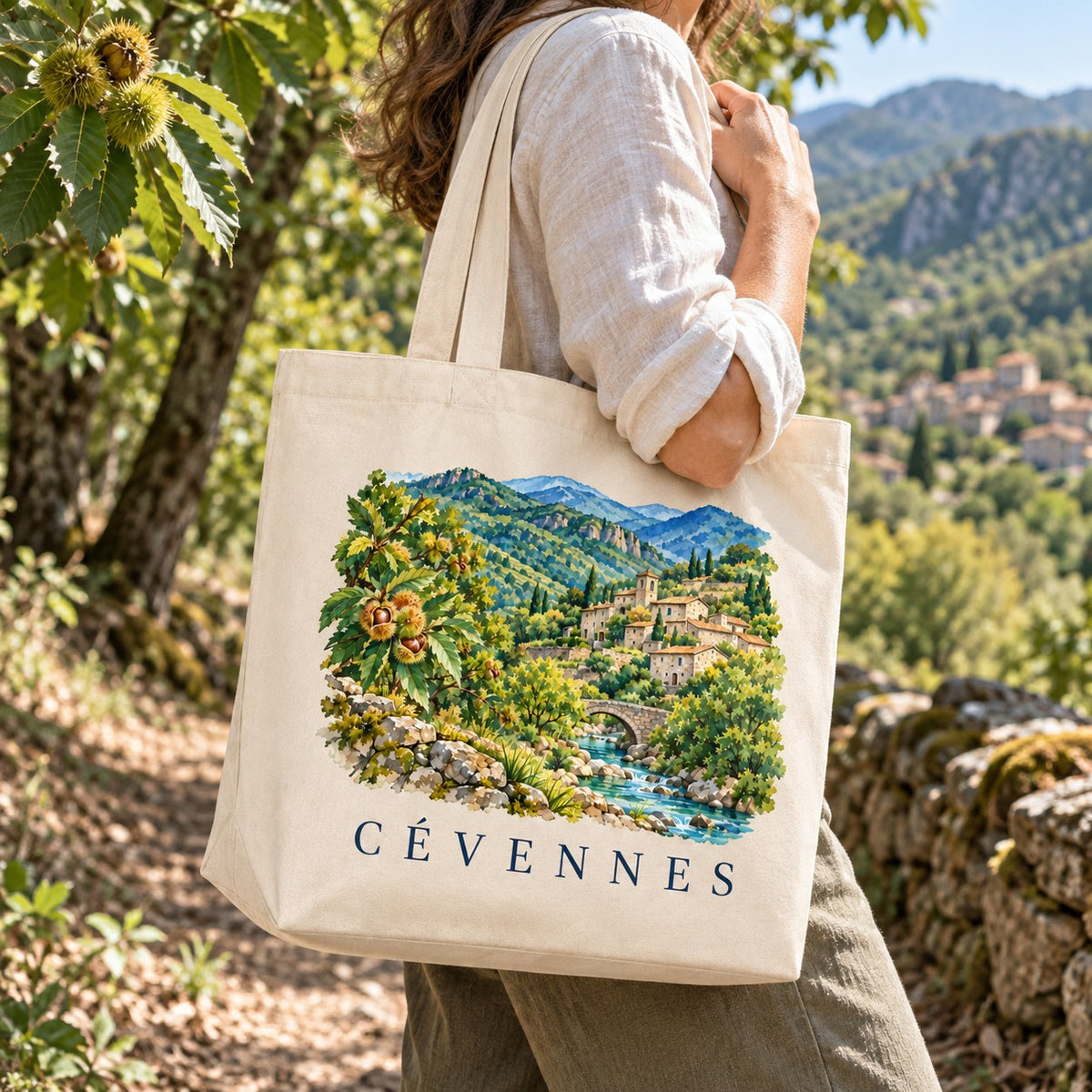 Tote bag Cévennes Premium porté à l'épaule sur un sentier sous les châtaigniers