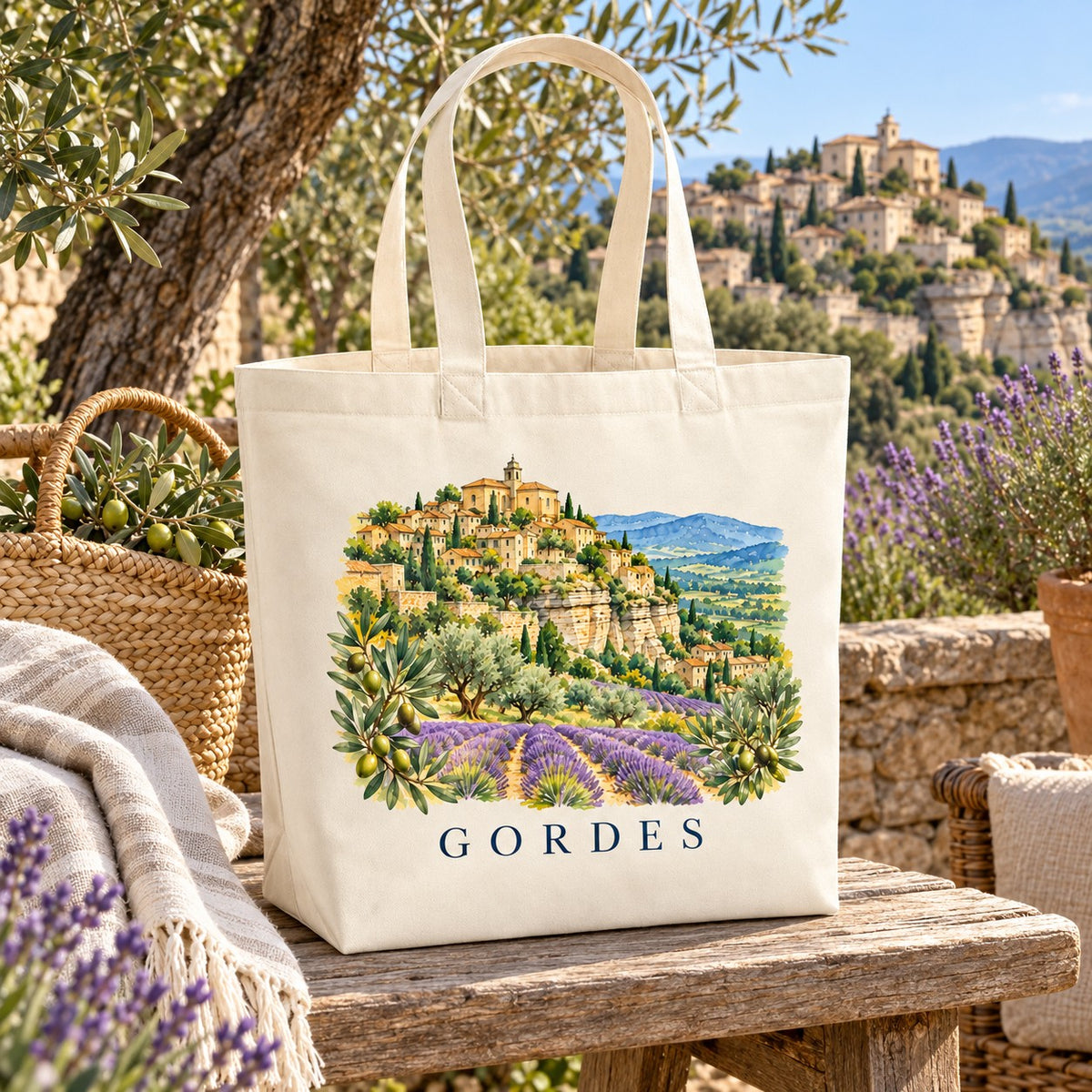 Tote bag Gordes Premium posé sur un muret de pierre, à côté d'un panier, d'un plaid et de brins de lavande