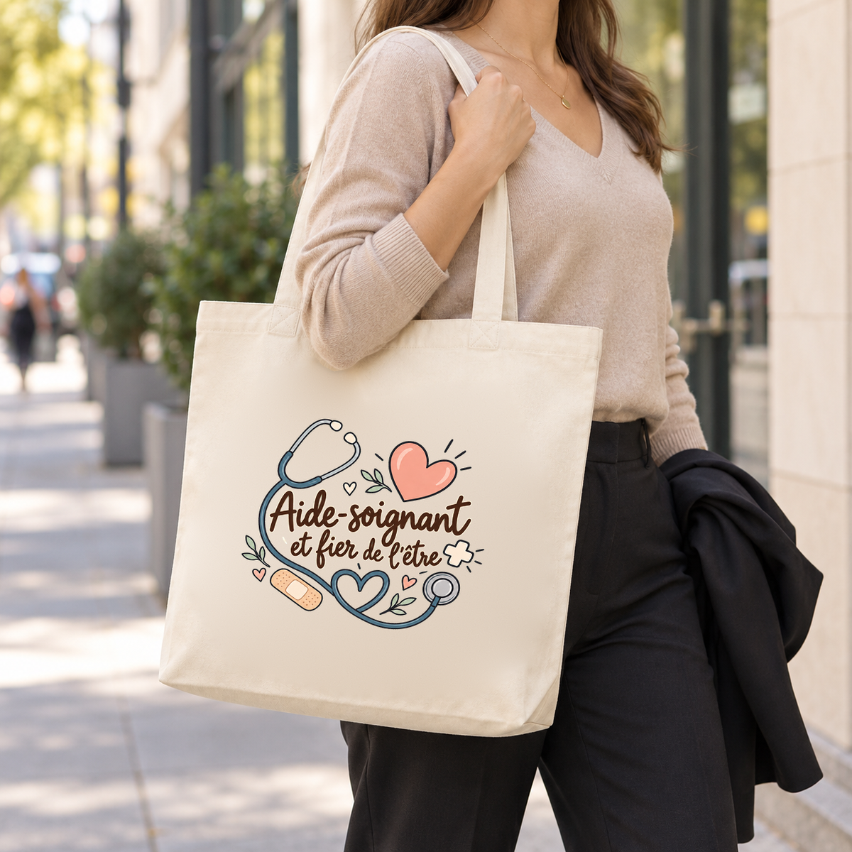 Tote bag aide-soignant « Aide-soignant et fier de l'être » Premium porté à l'épaule en sortant de l'hôpital, une veste sur le bras