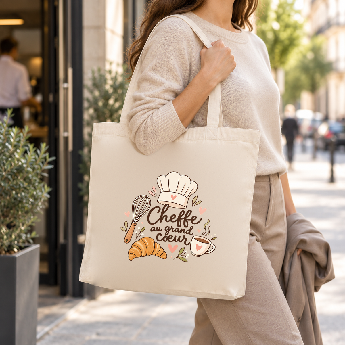 Tote bag cheffe cuisinière « Cheffe au grand cœur » Premium porté à l'épaule dans la rue, une veste sur le bras