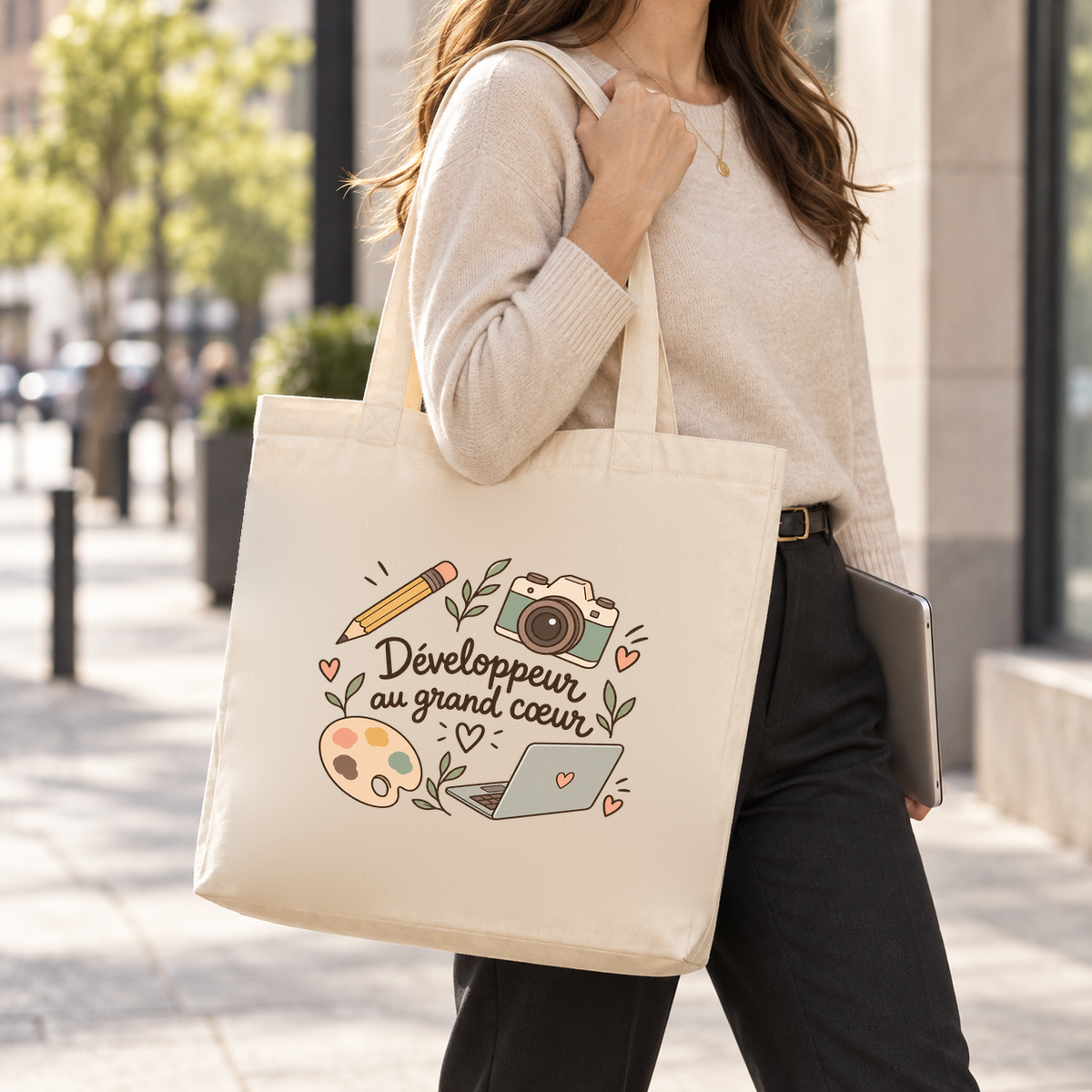 Tote bag développeur « Développeur au grand cœur » Premium porté à l'épaule dans la rue, un ordinateur sous le bras
