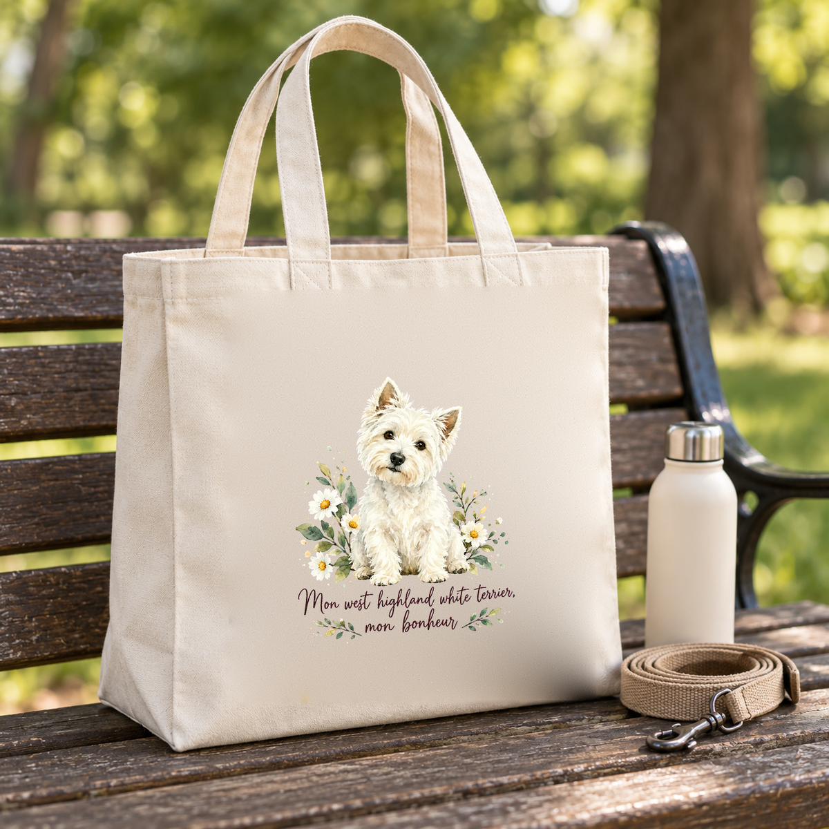 Tote bag west highland white terrier Premium posé sur un banc de parc, à côté d'une gourde et d'une laisse