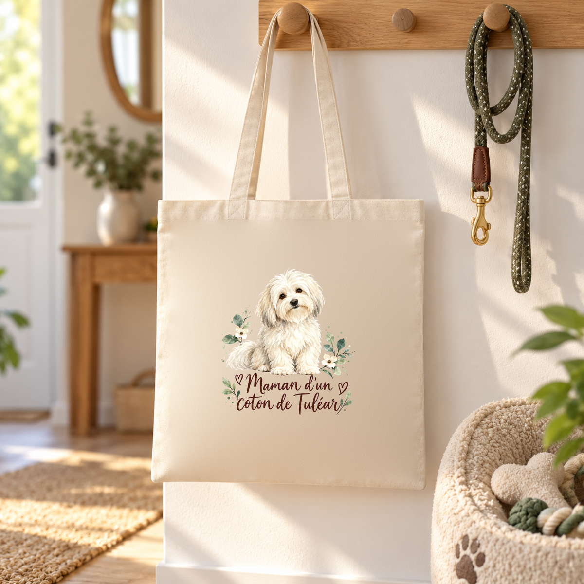 Tote bag coton de Tuléar « Maman d'un coton de Tuléar » Essentiel suspendu à une patère dans l'entrée, à côté d'une laisse et d'un panier pour chien