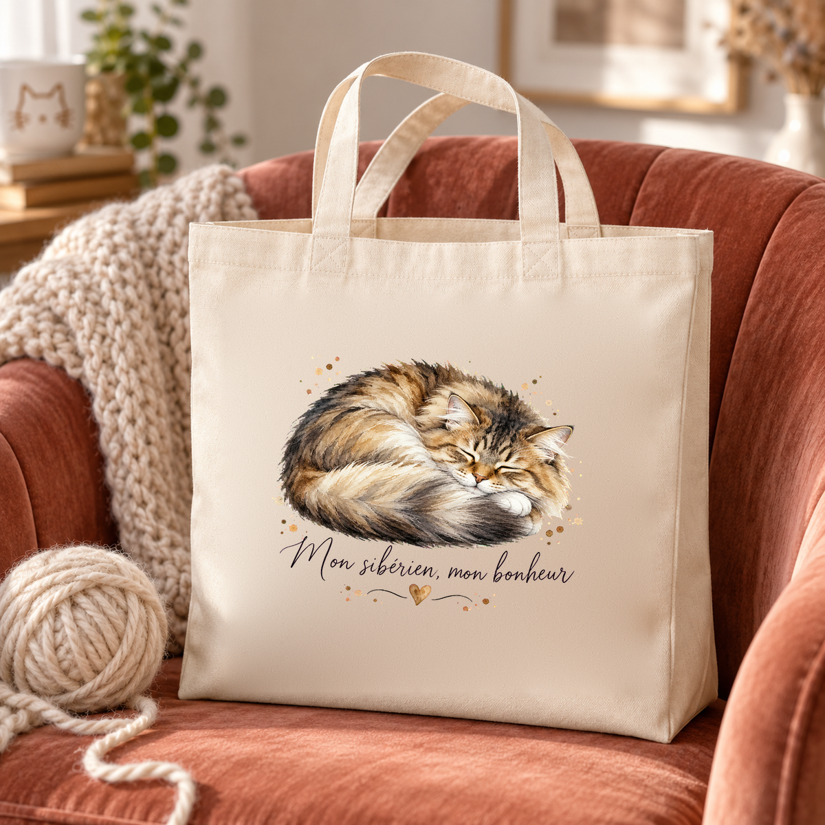 Tote bag sibérien « Mon sibérien, mon bonheur » Premium posé sur un fauteuil en velours rose, à côté d'un plaid et d'une pelote de laine