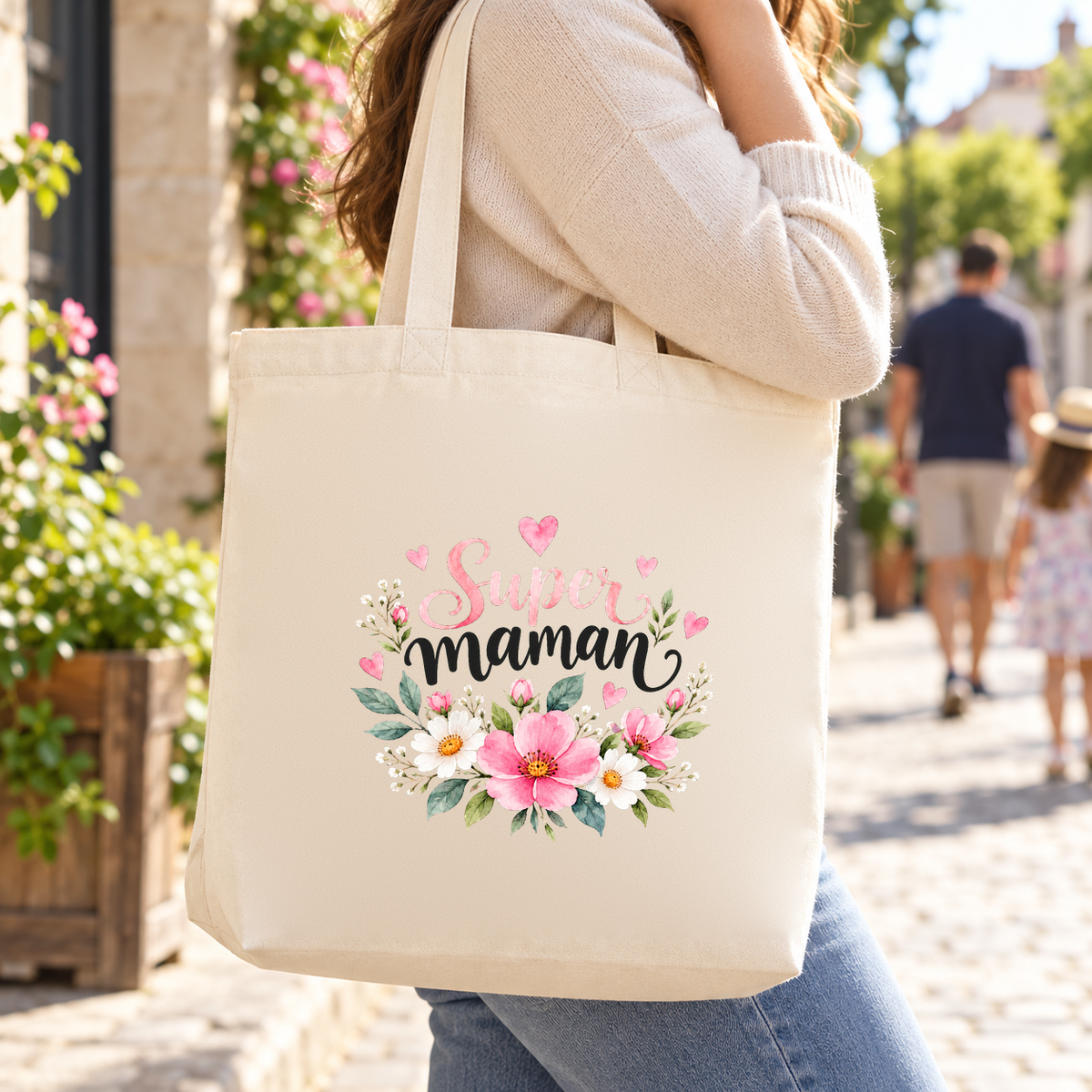 Tote bag maman « Super maman » Premium porté à l'épaule dans une ruelle ensoleillée