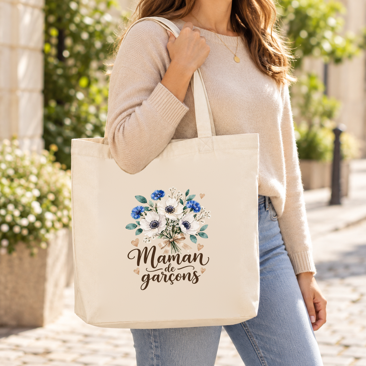Tote bag maman « Maman de garçons » Premium porté à l'épaule dans une rue ensoleillée