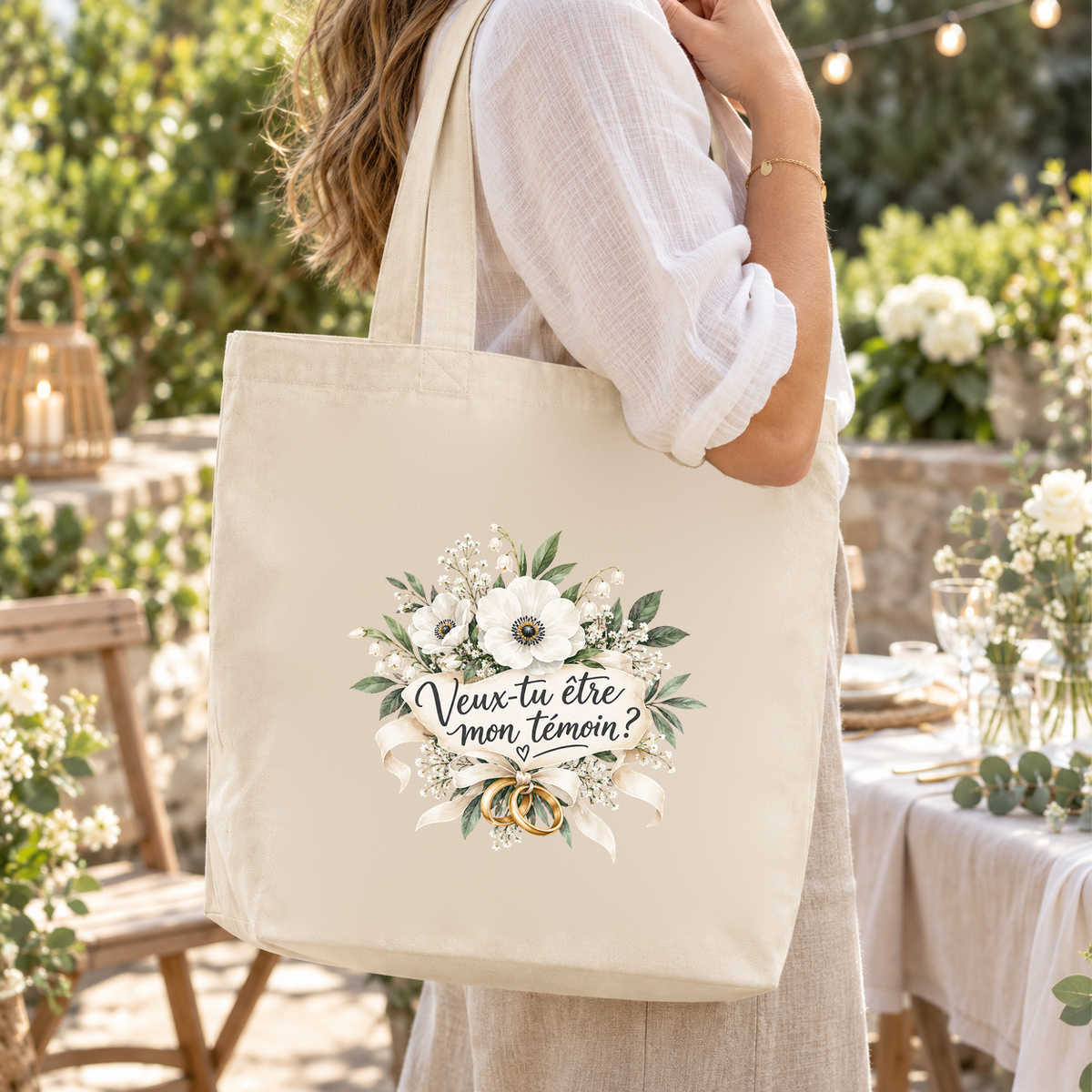 Tote bag témoin « Veux-tu être mon témoin ? » Premium porté à l'épaule lors d'une réception de mariage dans un jardin