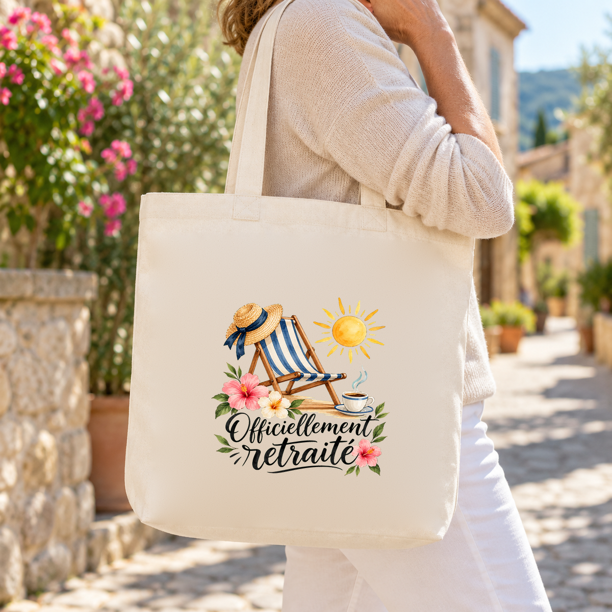 Tote bag retraite « Officiellement retraité » Premium porté à l'épaule dans une ruelle ensoleillée, lors d'une promenade