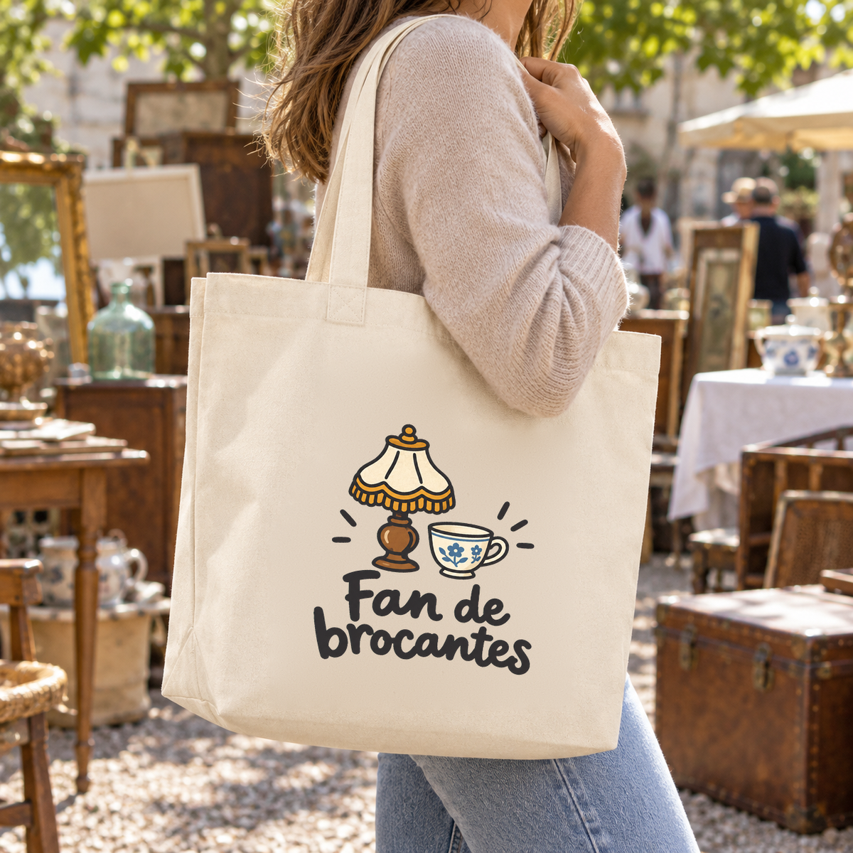 Tote bag « Fan de brocantes » Premium porté à l'épaule dans une brocante en plein air