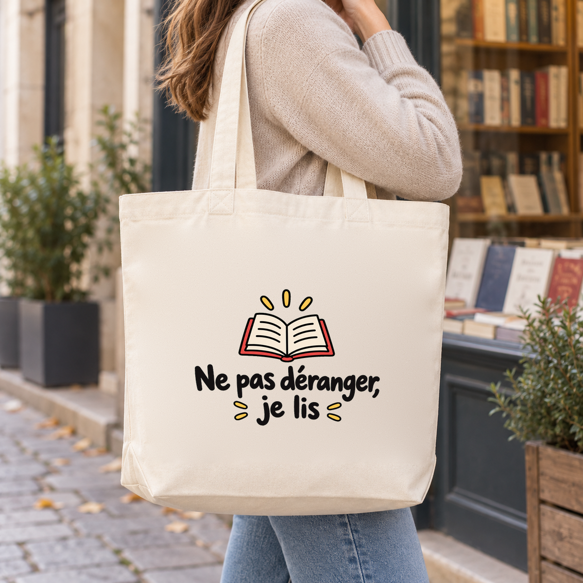 Tote bag « Ne pas déranger, je lis » Premium porté à l'épaule devant une librairie