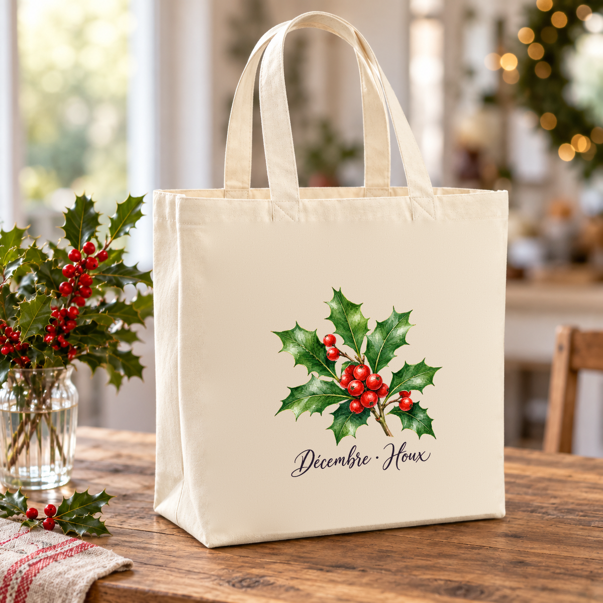 Tote bag fleur de naissance « Décembre · Houx » Premium posé sur une table, à côté d'un vase de houx