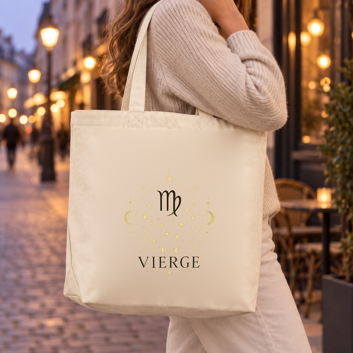 Tote bag signe astrologique « VIERGE » Premium porté à l'épaule dans une rue pavée illuminée au crépuscule