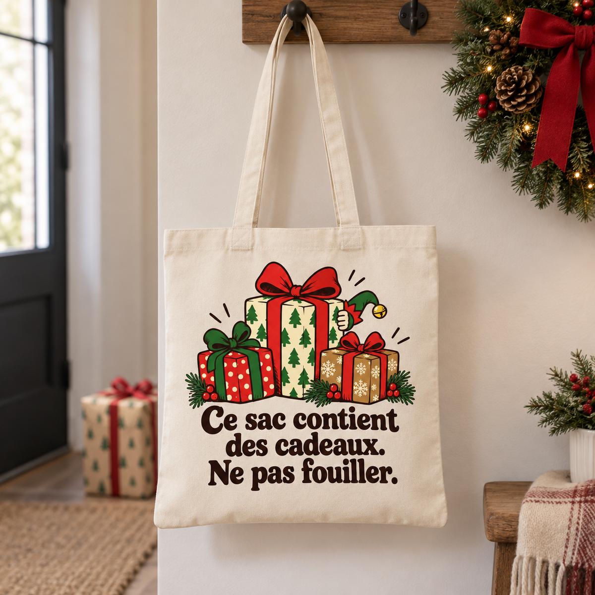Tote bag Noël « Ce sac contient des cadeaux. Ne pas fouiller. » Essentiel suspendu par ses anses dans un intérieur décoré pour les fêtes