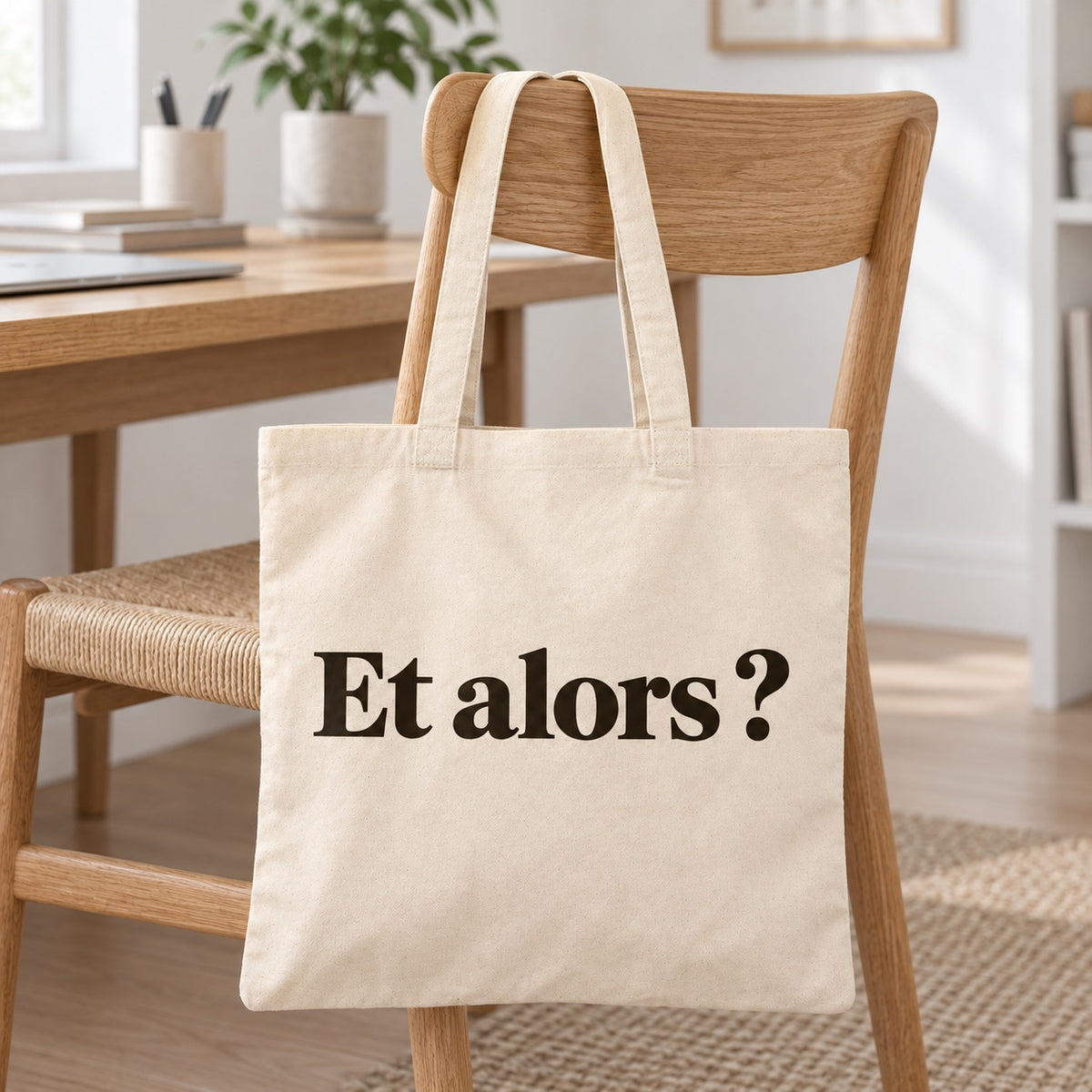 Tote bag « Et alors ? » Essentiel posé contre une chaise dans un intérieur clair