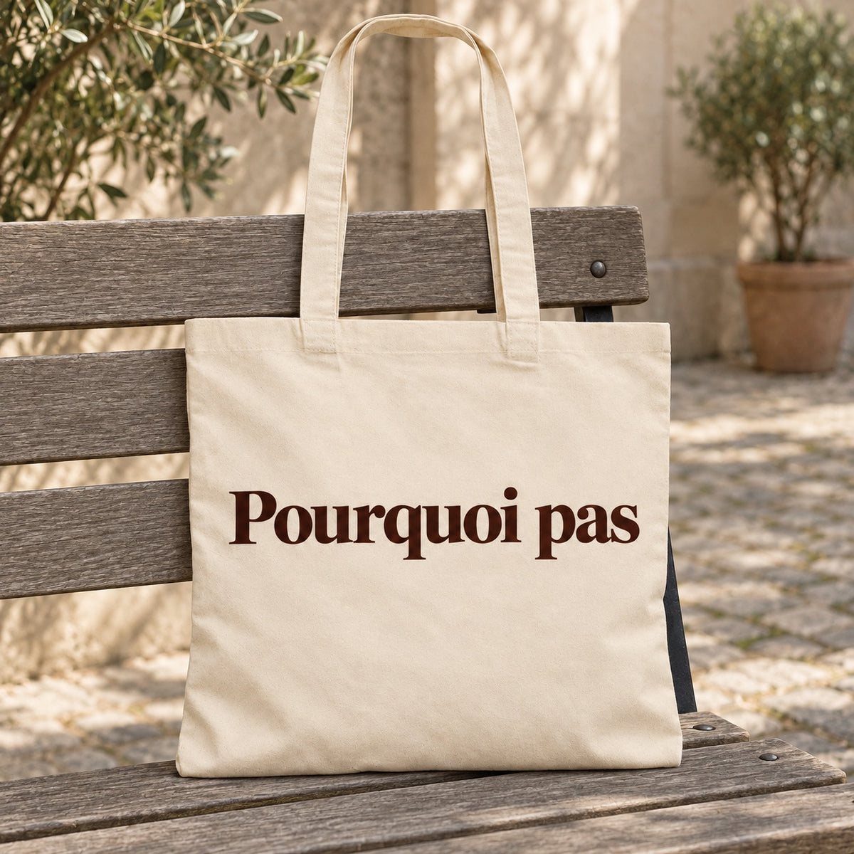 Tote bag « Pourquoi pas » Essentiel posé contre une chaise dans un intérieur clair
