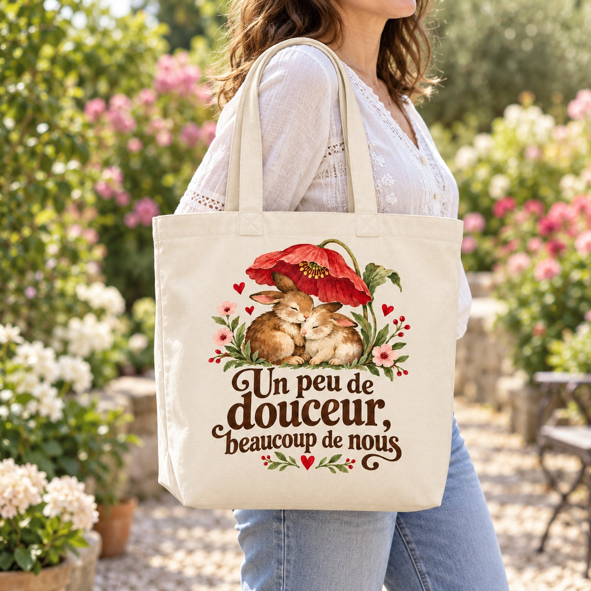 Tote bag « Un peu de douceur, beaucoup de nous » Premium porté à l'épaule dans un jardin fleuri