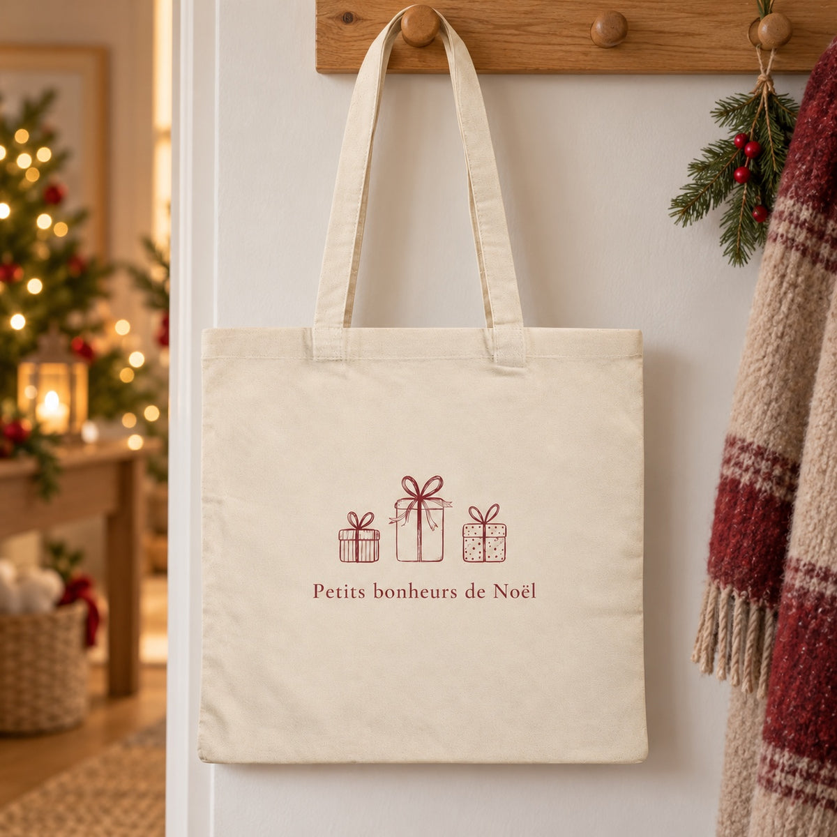 Tote bag de Noël « Petits bonheurs de Noël » Essentiel suspendu à une patère dans une entrée décorée pour Noël