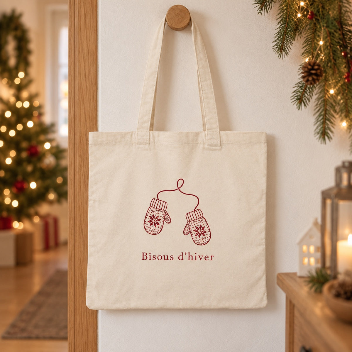 Tote bag de Noël « Bisous d’hiver » Essentiel suspendu à une patère dans une entrée décorée pour Noël