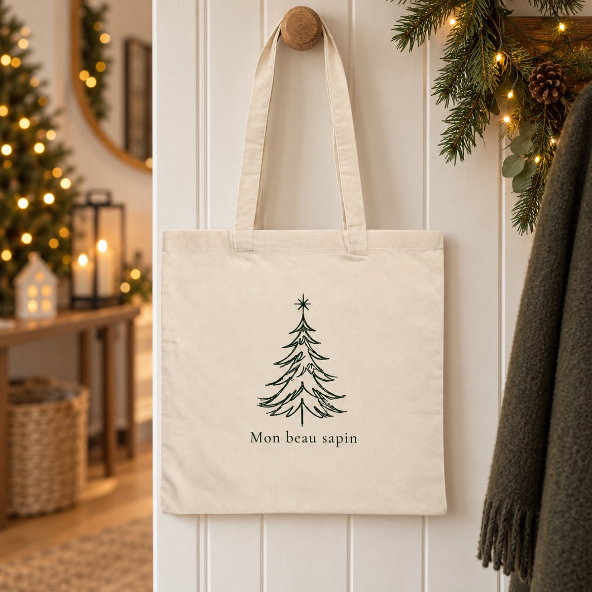 Tote bag de Noël « Mon beau sapin » Essentiel suspendu à une patère dans une entrée décorée pour Noël