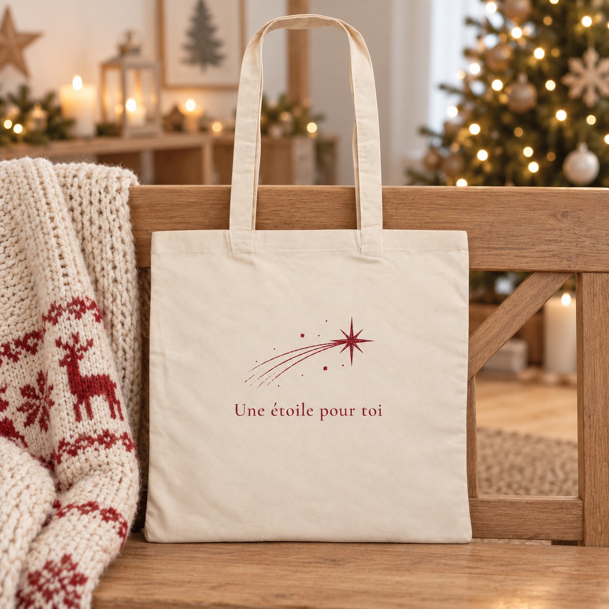 Tote bag de Noël « Une étoile pour toi » Essentiel appuyé contre un banc près d'un plaid de Noël