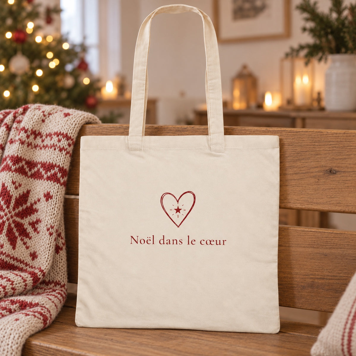 Tote bag de Noël « Noël dans le cœur » Essentiel appuyé contre un banc près d'un plaid de Noël