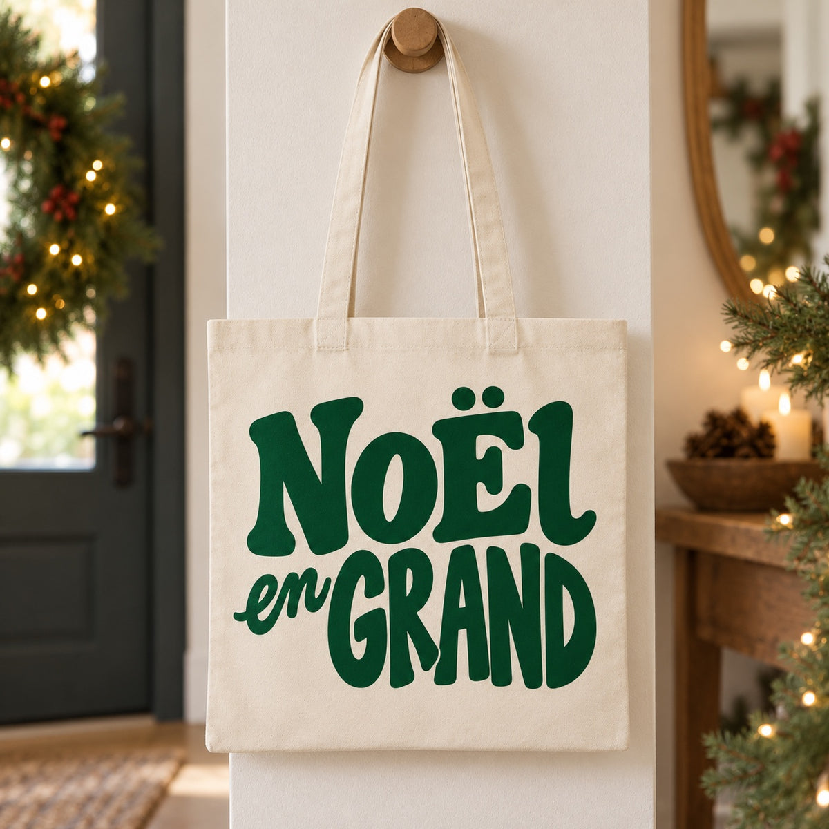 Tote bag de Noël « Noël en grand » Essentiel suspendu à une patère dans une entrée décorée pour Noël