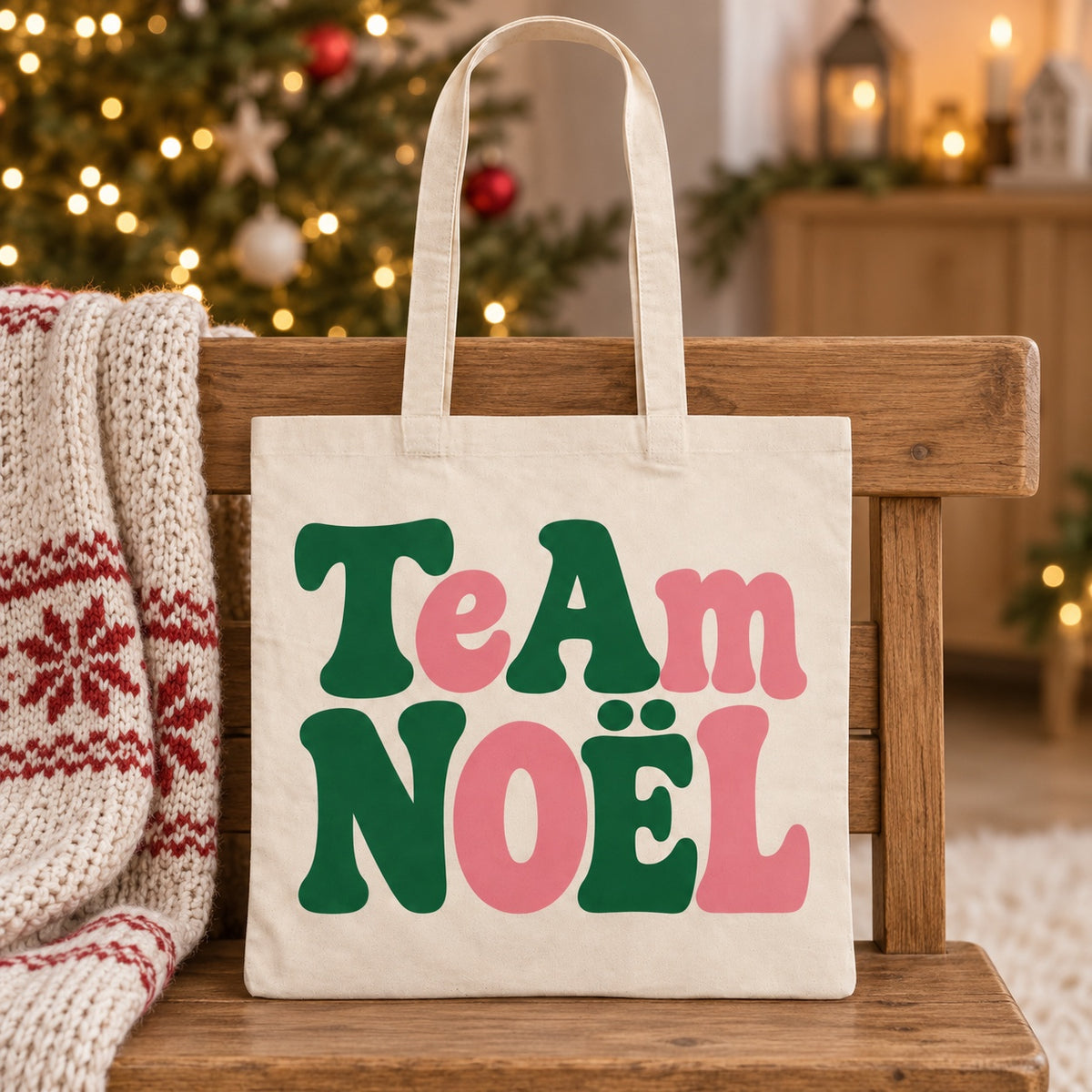 Tote bag de Noël « Team Noël » Essentiel appuyé contre un banc près d'un plaid de Noël