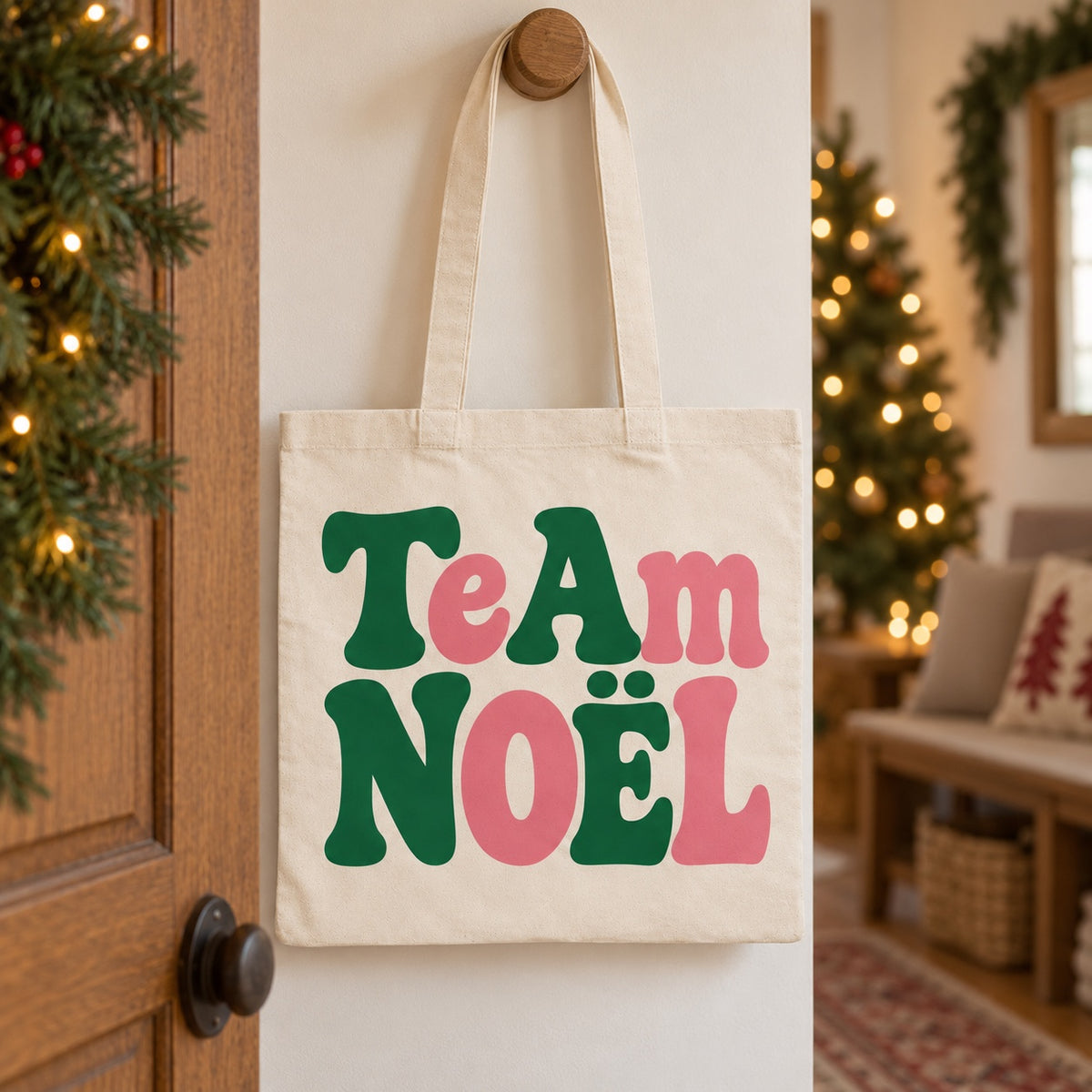 Tote bag de Noël « Team Noël » Essentiel suspendu à une patère dans une entrée décorée pour Noël