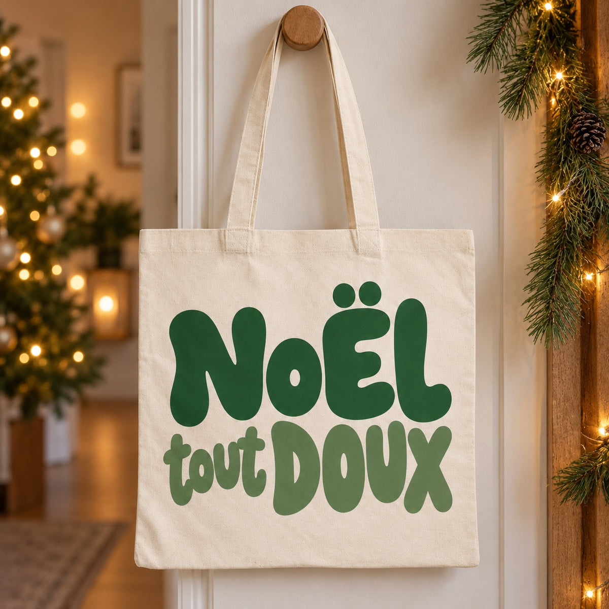 Tote bag de Noël « Noël tout doux » Essentiel suspendu à une patère dans une entrée décorée pour Noël