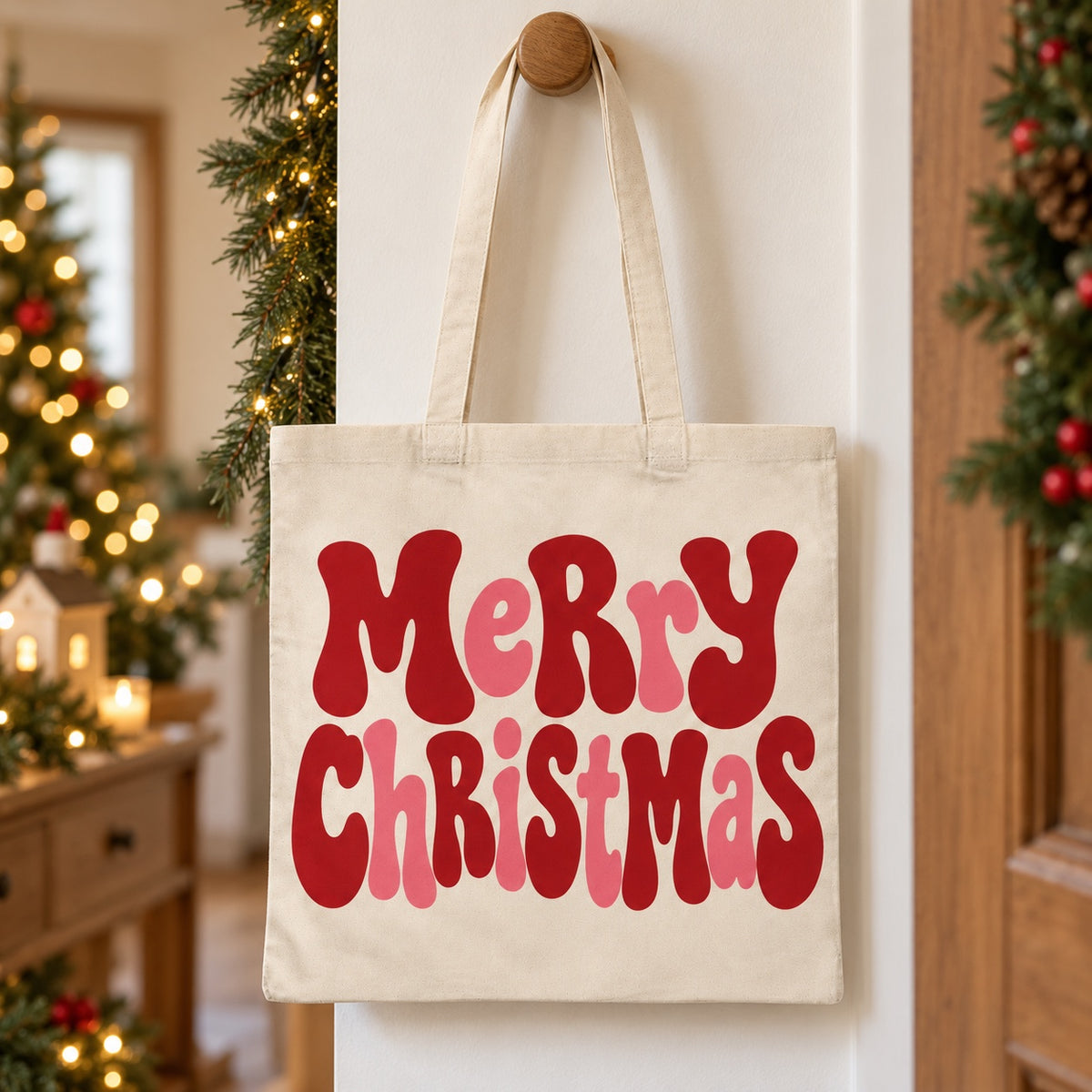 Tote bag de Noël « Merry Christmas » Essentiel suspendu à une patère dans une entrée décorée pour Noël