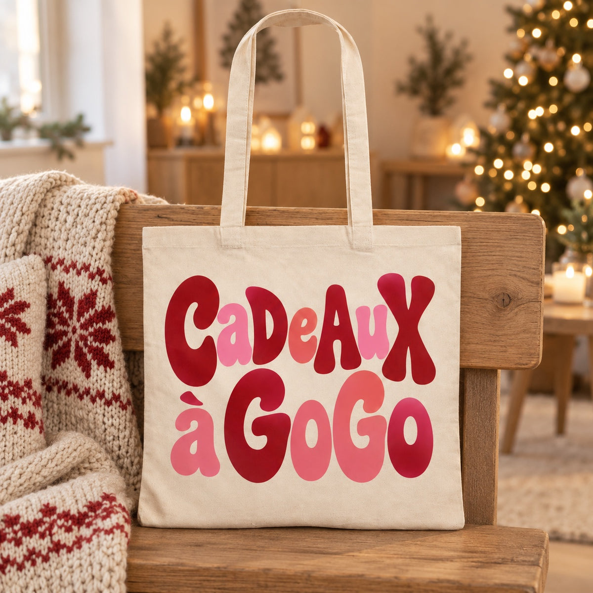 Tote bag de Noël « Cadeaux à gogo » Essentiel appuyé contre un banc près d'un plaid de Noël