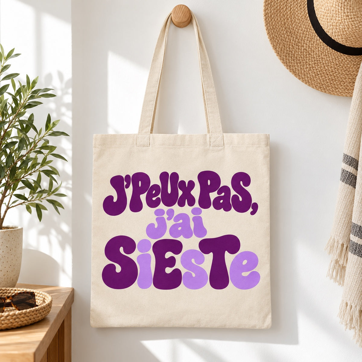 Tote bag « J'peux pas, j'ai sieste » Essentiel suspendu à une patère dans une entrée