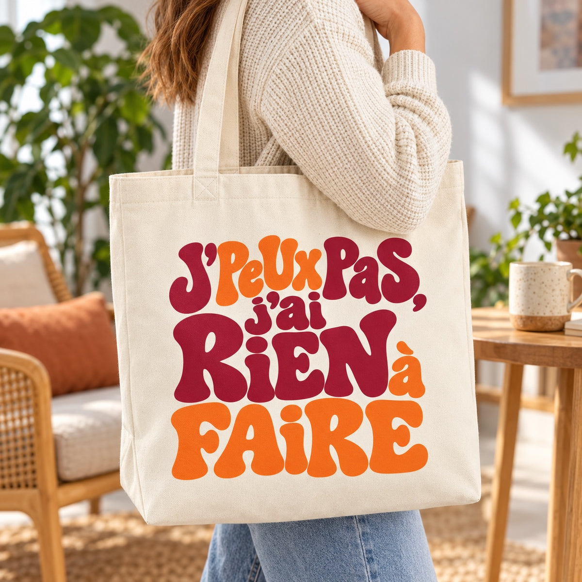 Tote bag « J'peux pas, j'ai rien à faire » Premium porté à l'épaule dans un salon lumineux