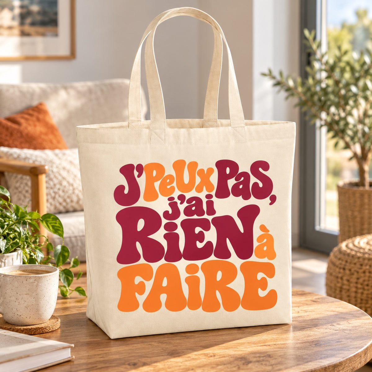 Tote bag « J'peux pas, j'ai rien à faire » Premium posé sur une table ronde dans un salon
