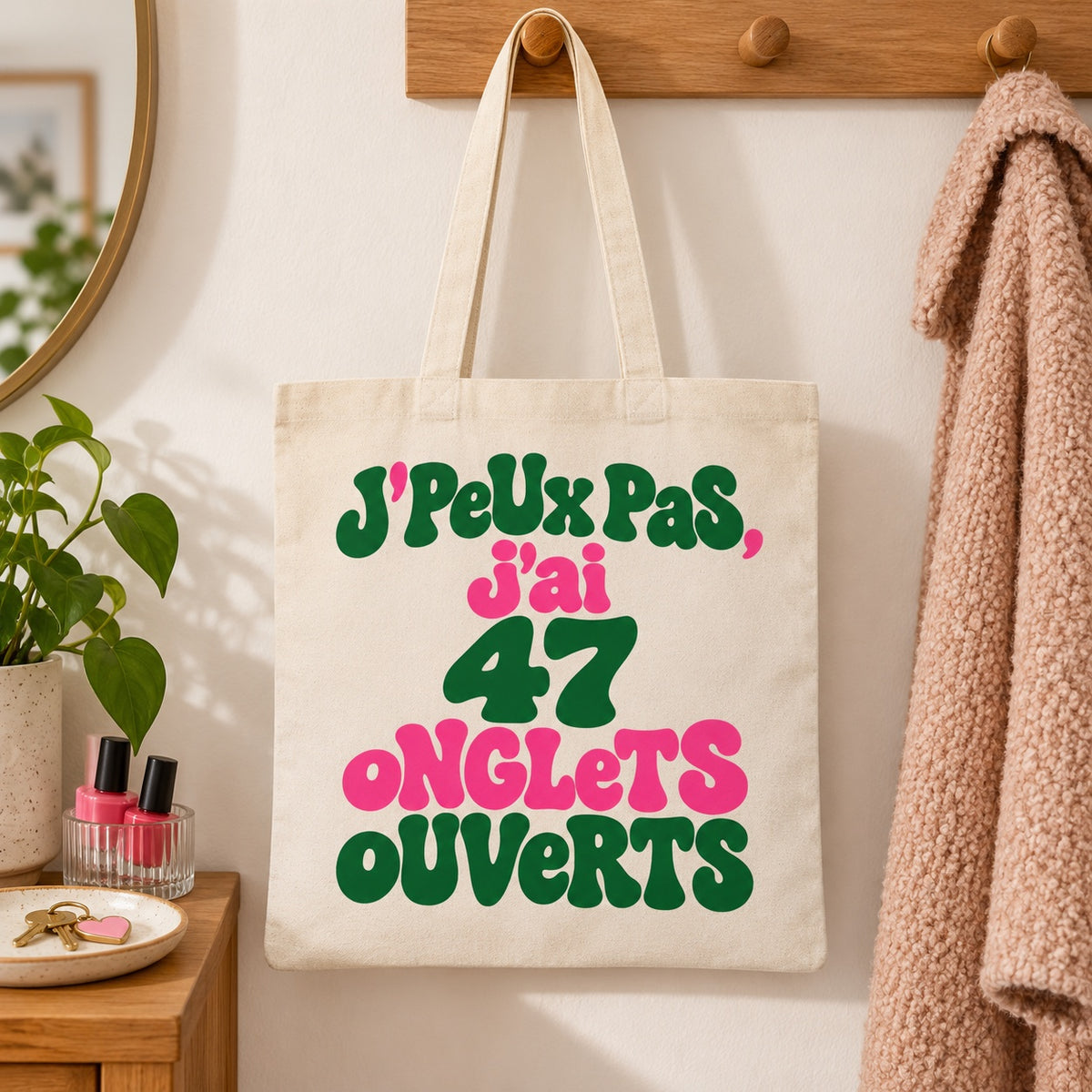 Tote bag « J'peux pas, j'ai 47 onglets ouverts » Essentiel suspendu à une patère dans une entrée