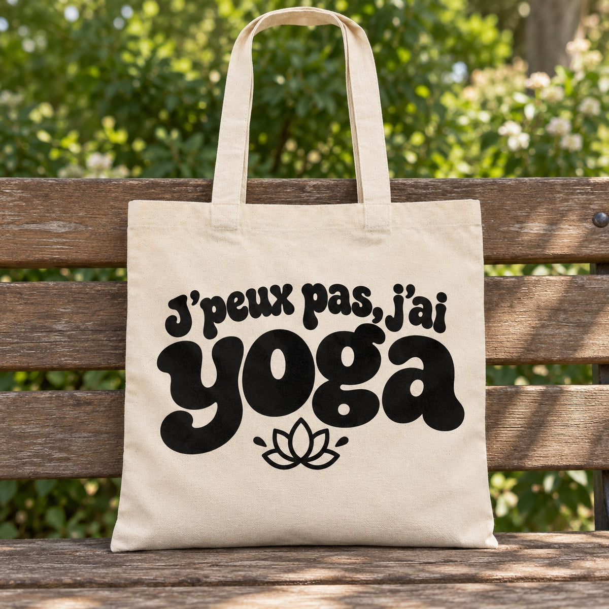 Tote bag « J'peux pas, j'ai yoga » Essentiel posé sur un banc en bois dans un jardin