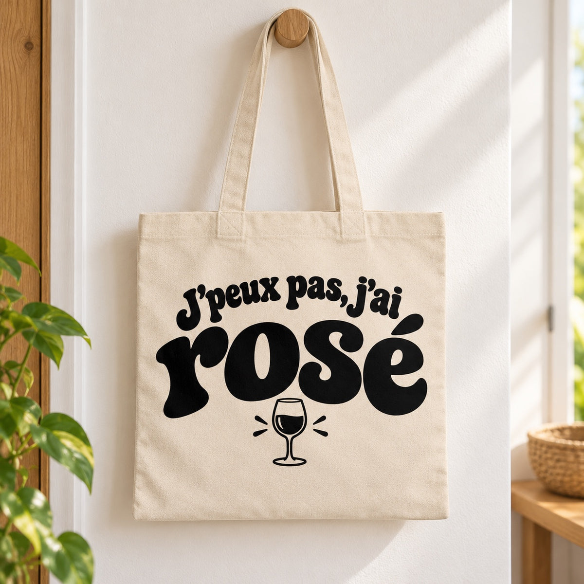 Tote bag « J'peux pas, j'ai rosé » Essentiel suspendu à une patère dans une entrée lumineuse