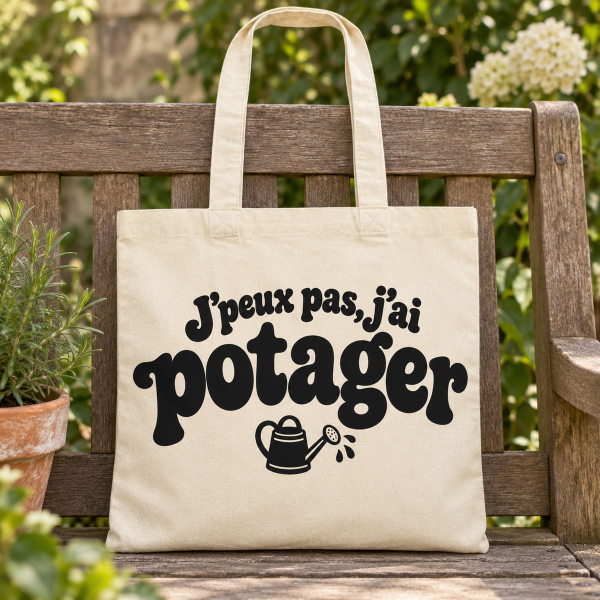 Tote bag « J'peux pas, j'ai potager » Essentiel posé sur un banc en bois dans un jardin