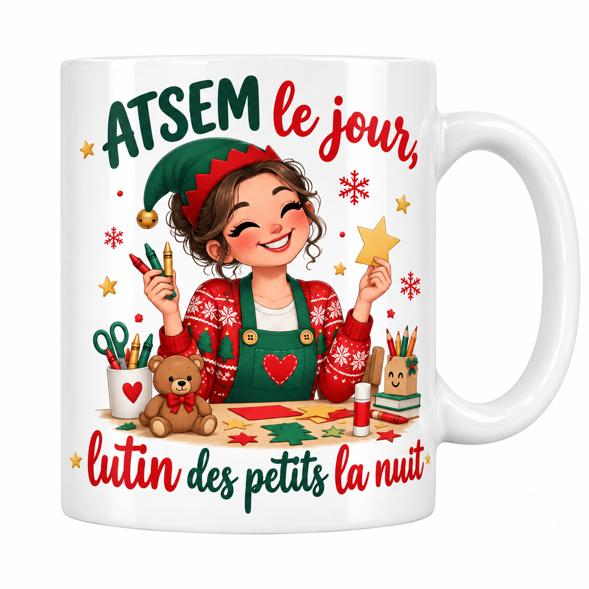 Mug blanc céramique de Noël « ATSEM le jour, lutin des petits la nuit » : une ATSEM en bonnet de lutin et pull de Noël découpe des étoiles et des sapins en papier, entourée de crayons, de colle et d'un petit ourson