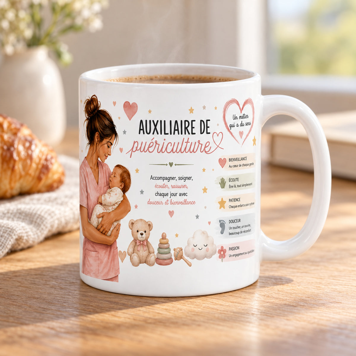 Mug Auxiliaire de Puériculture « Veiller sur les Tout-Petits » posé sur une table en bois avec un croissant, pause café
