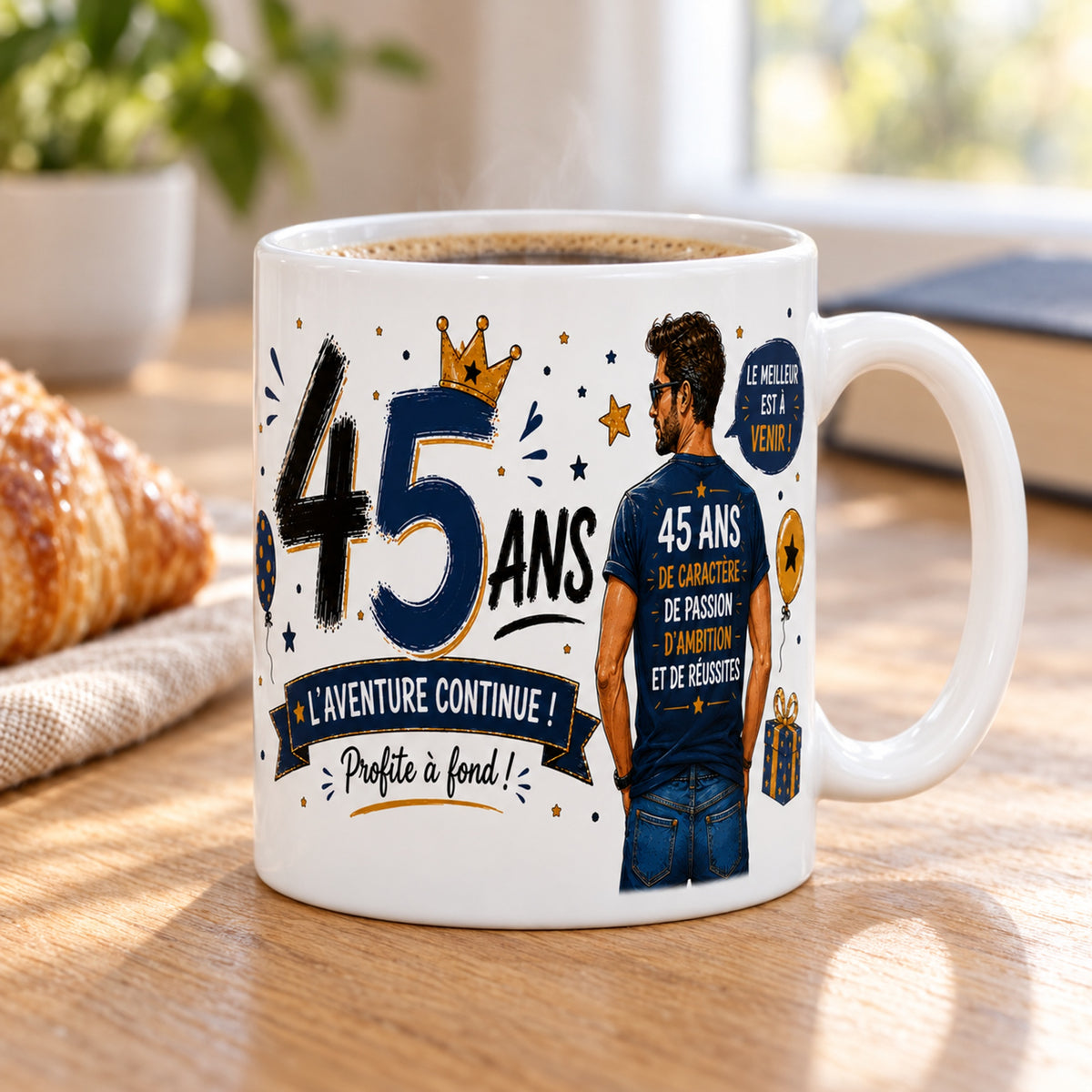 Mug 45 ans Homme « Le Meilleur est à Venir » posé sur une table en bois avec un croissant, pause café
