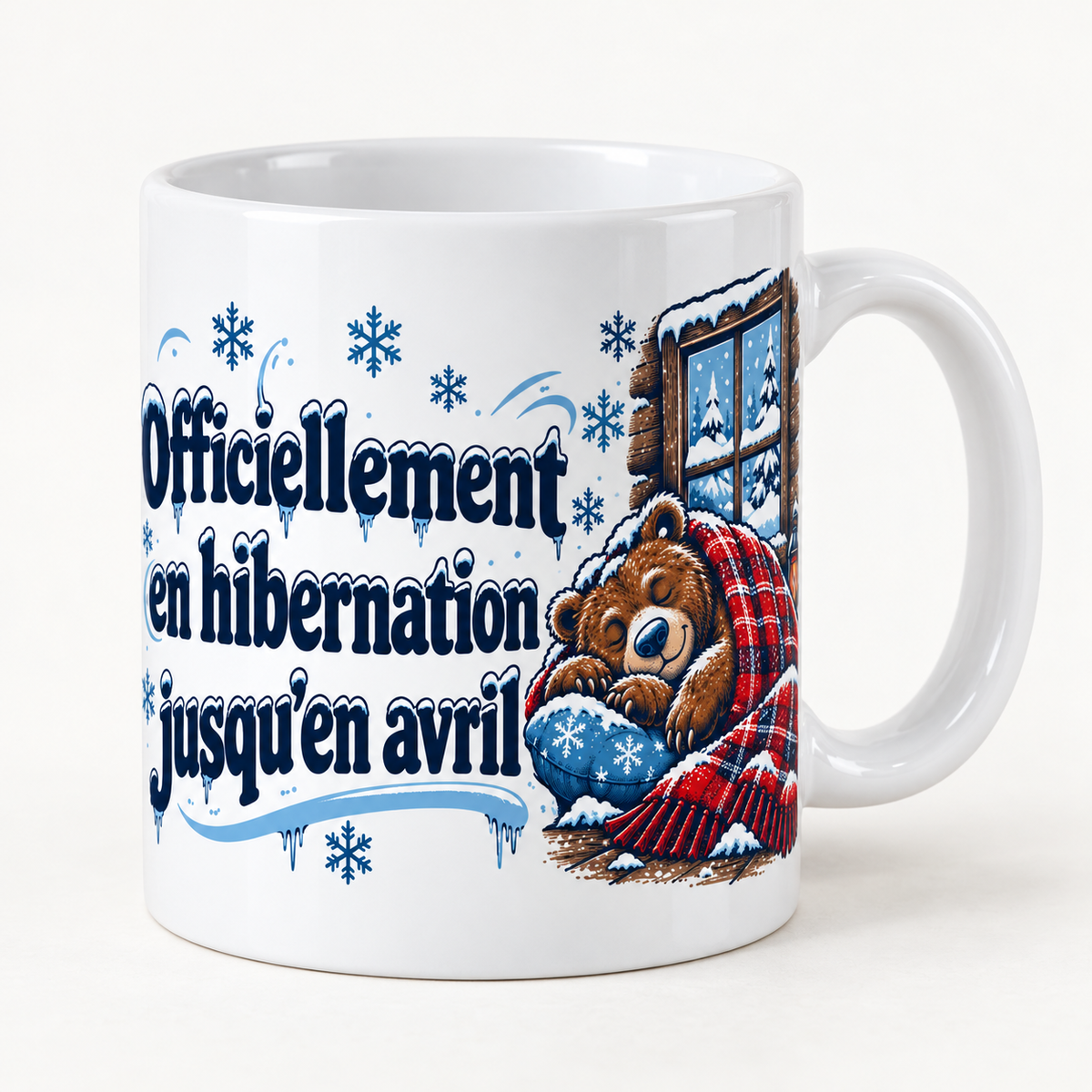 Mug blanc céramique Hiver québécois « Officiellement en hibernation jusqu’en avril » : un ours brun dort à poings fermés, roulé dans une couverture à carreaux rouges, devant la fenêtre d'un chalet où tombe la neige, une lanterne allumée à ses côtés