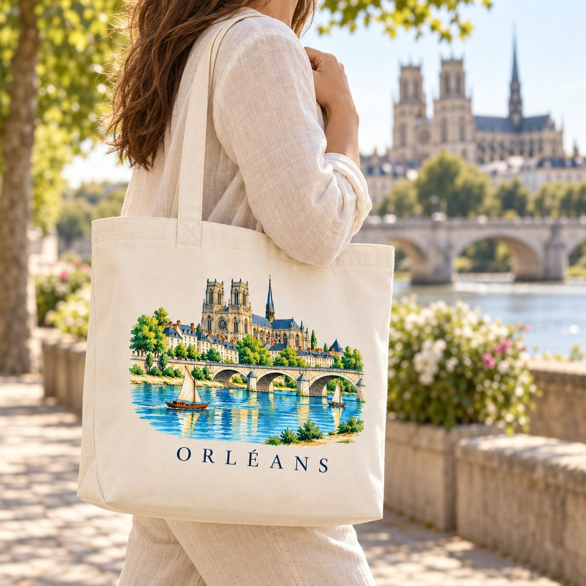 Tote bag Orléans Premium porté à l'épaule sur les quais de Loire, cathédrale en arrière-plan